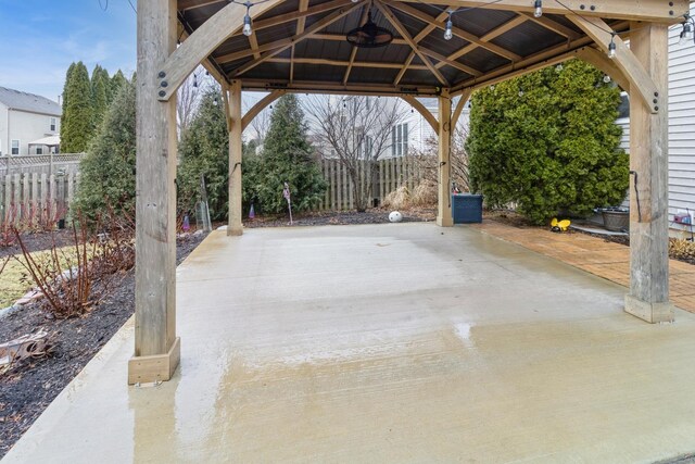 view of patio with a carport, concrete driveway, and fence