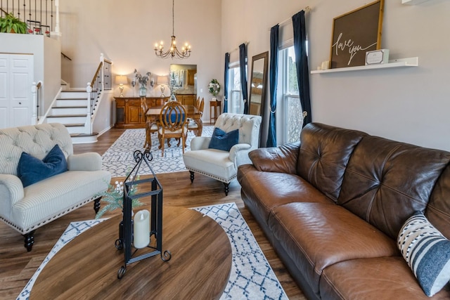 living room featuring stairs, wood finished floors, a chandelier, and a high ceiling