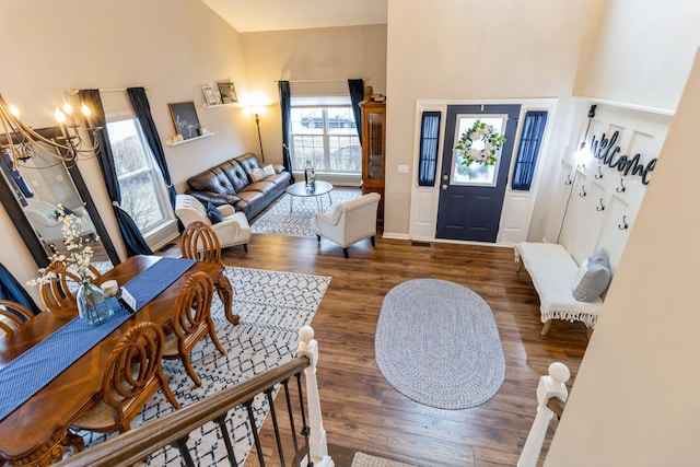 entryway featuring baseboards, a notable chandelier, a high ceiling, and wood finished floors