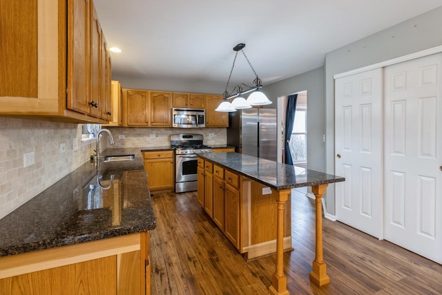 kitchen with appliances with stainless steel finishes, dark wood-type flooring, a sink, and decorative backsplash