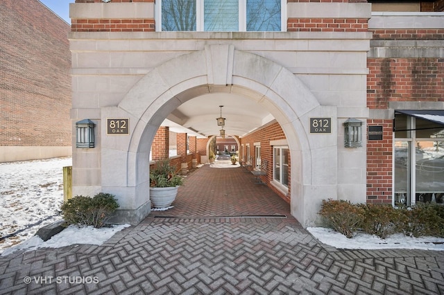 snow covered property entrance with brick siding