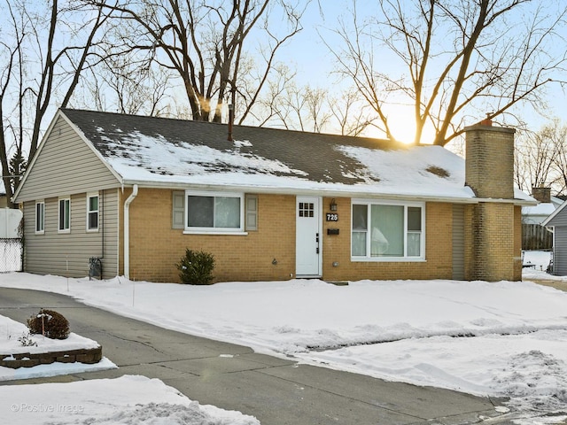 single story home featuring a chimney and brick siding