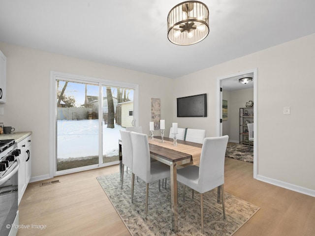 dining room featuring light wood-style floors, baseboards, visible vents, and a chandelier