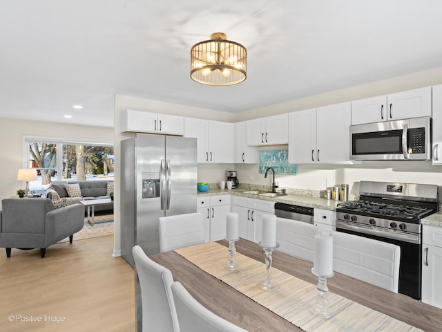 kitchen featuring stainless steel appliances, white cabinetry, and a sink