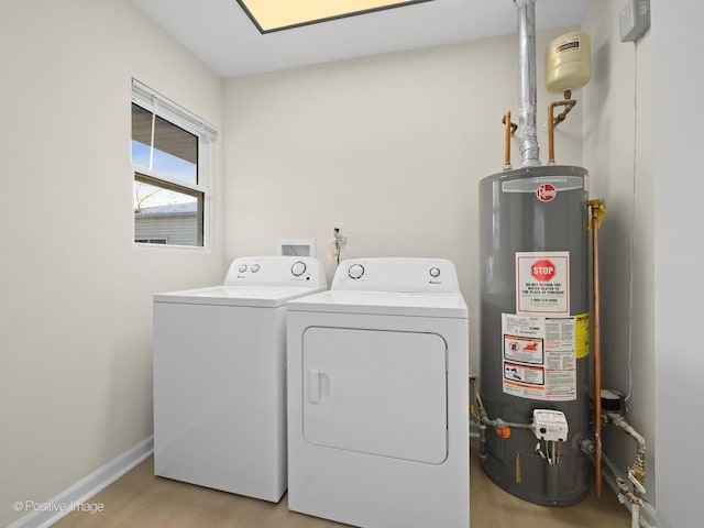 clothes washing area with laundry area, baseboards, washer and clothes dryer, light wood-style flooring, and water heater