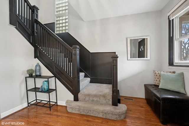 stairs featuring wood finished floors, visible vents, and baseboards