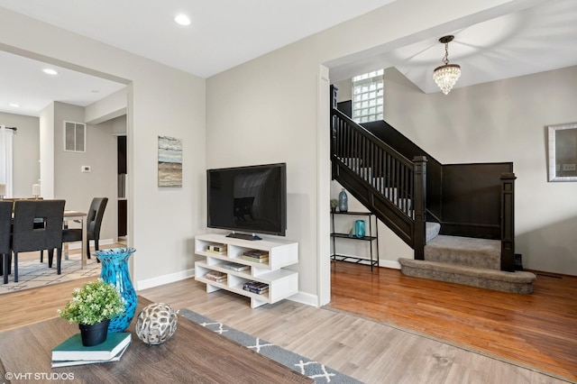 living area featuring visible vents, stairway, baseboards, and wood finished floors