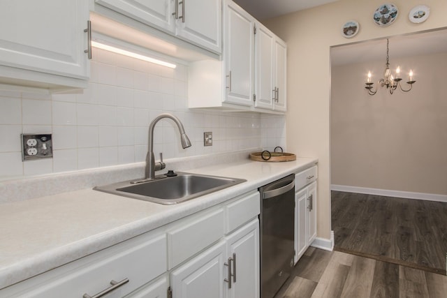 kitchen featuring decorative backsplash, light countertops, stainless steel dishwasher, white cabinetry, and a sink