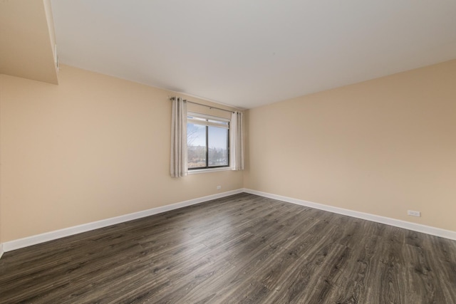 empty room with dark wood-style flooring and baseboards