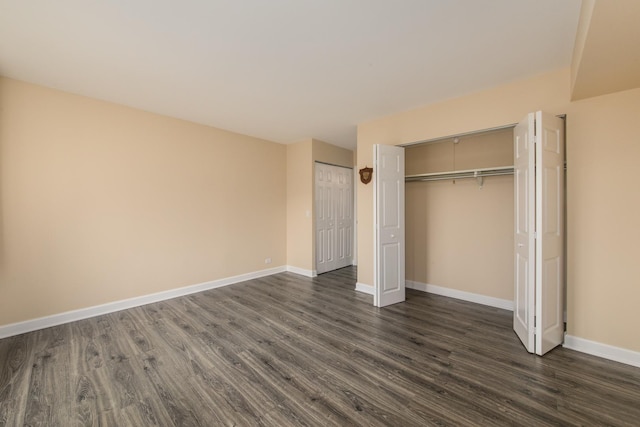 unfurnished bedroom featuring two closets, baseboards, and dark wood-style flooring