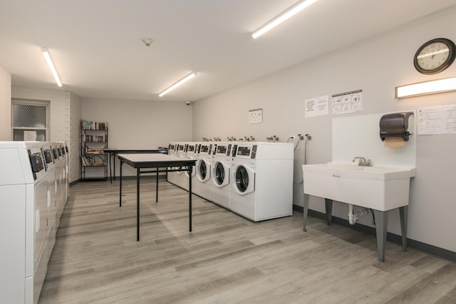 common laundry area with baseboards, light wood finished floors, a sink, and washer and dryer