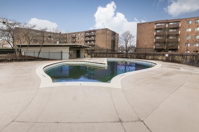 pool with a patio area and fence