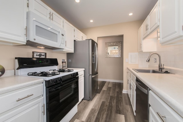 kitchen with dark wood-type flooring, a sink, white cabinets, appliances with stainless steel finishes, and decorative backsplash