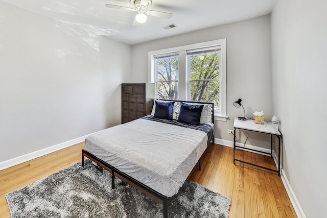 bedroom featuring baseboards, visible vents, ceiling fan, and wood finished floors