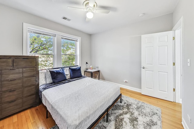 bedroom featuring light wood-type flooring, visible vents, ceiling fan, and baseboards