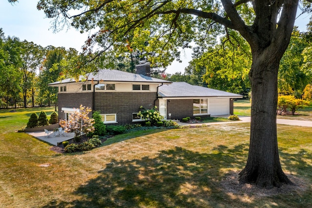 view of front of house featuring brick siding, a patio, an attached garage, and a front lawn