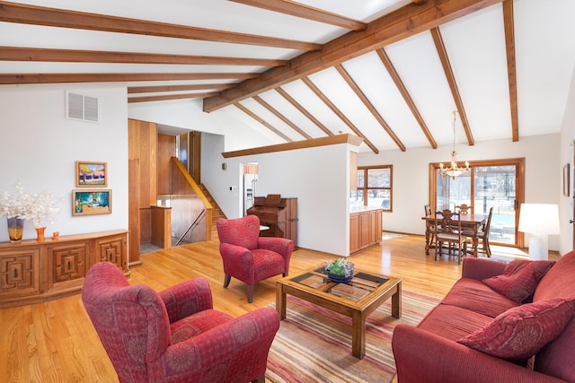 living area with lofted ceiling with beams, visible vents, an inviting chandelier, and light wood finished floors