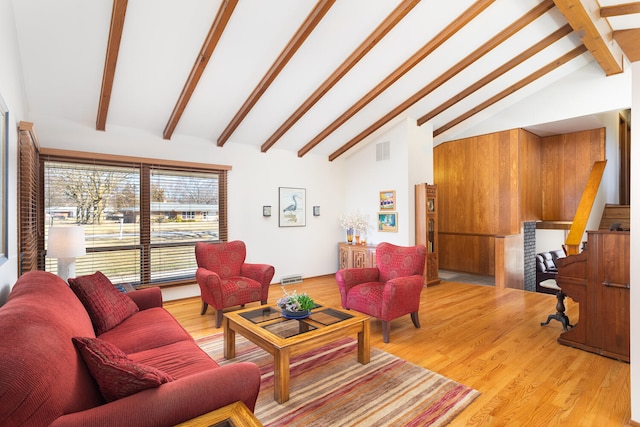 living area featuring visible vents, lofted ceiling with beams, and wood finished floors