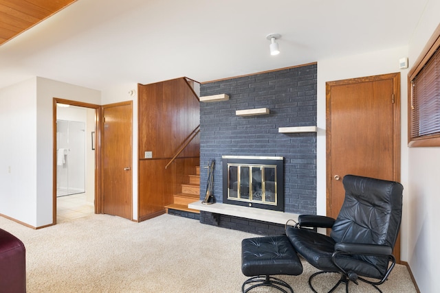 living area featuring stairs, a brick fireplace, carpet, and baseboards