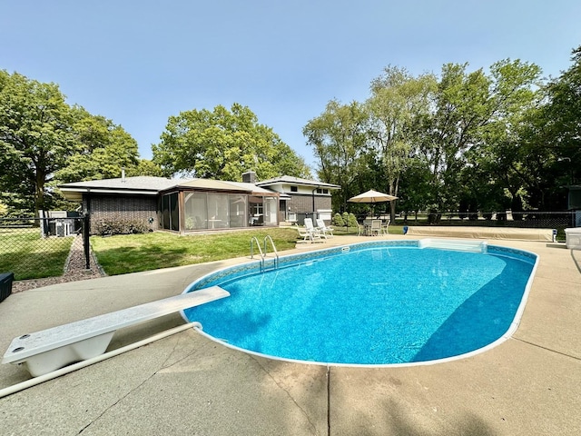 pool with a patio, a yard, fence, and a diving board