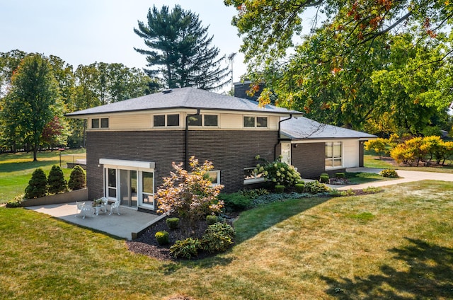 rear view of property featuring a yard, a chimney, and a patio