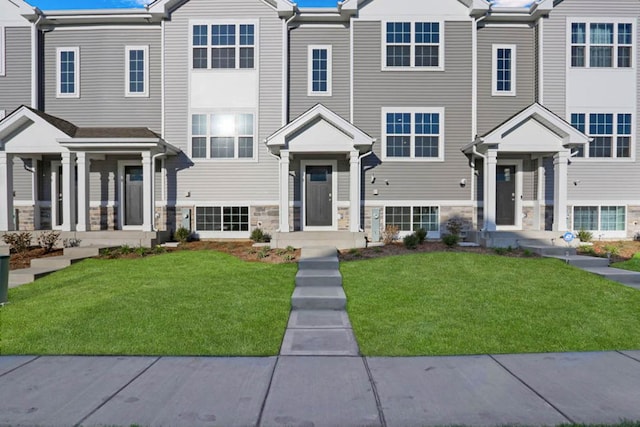 view of property with stone siding and a front lawn