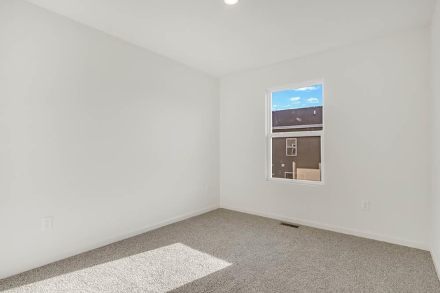 unfurnished room featuring carpet floors, visible vents, and baseboards