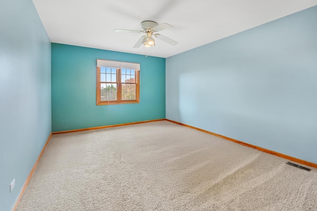 carpeted empty room with visible vents, ceiling fan, and baseboards