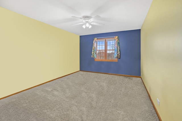 carpeted spare room with ceiling fan and baseboards