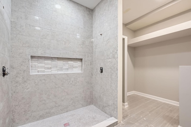 full bathroom featuring a tile shower, baseboards, and wood finished floors