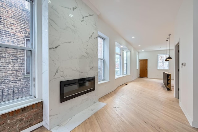 living area featuring baseboards, light wood-style flooring, a premium fireplace, heating unit, and recessed lighting