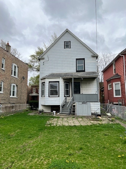 rear view of property featuring fence and a lawn