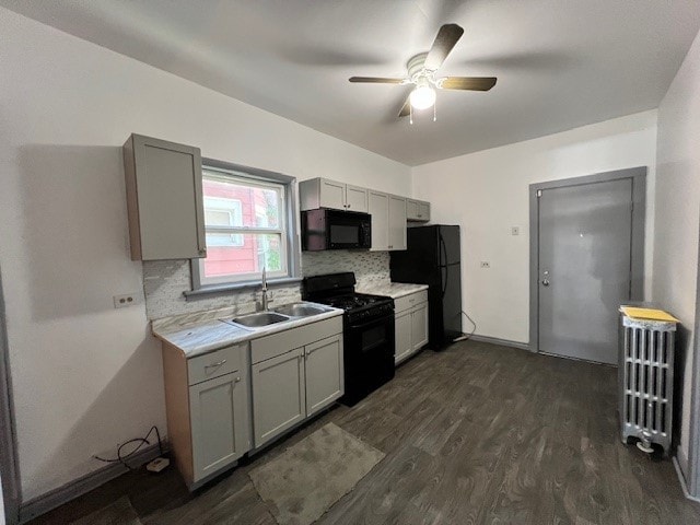 kitchen with radiator, gray cabinets, light countertops, black appliances, and a sink