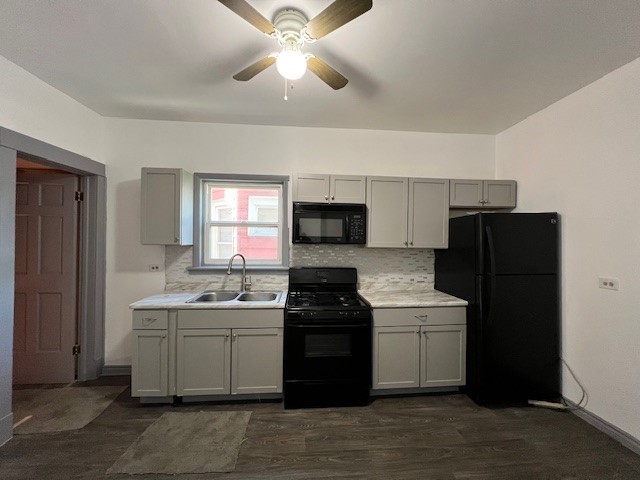 kitchen with a sink, black appliances, light countertops, and gray cabinetry