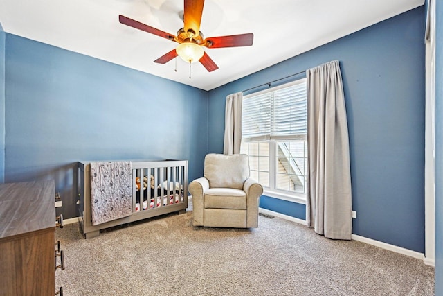 carpeted bedroom with a ceiling fan, visible vents, a crib, and baseboards