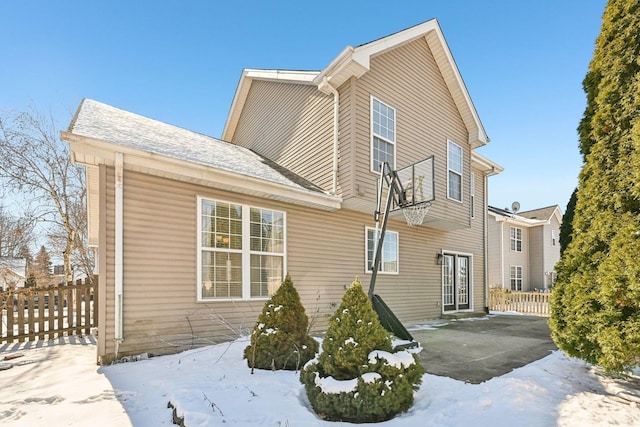 view of snow covered exterior with a patio area and fence