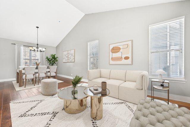 living area with high vaulted ceiling, a notable chandelier, baseboards, and wood finished floors