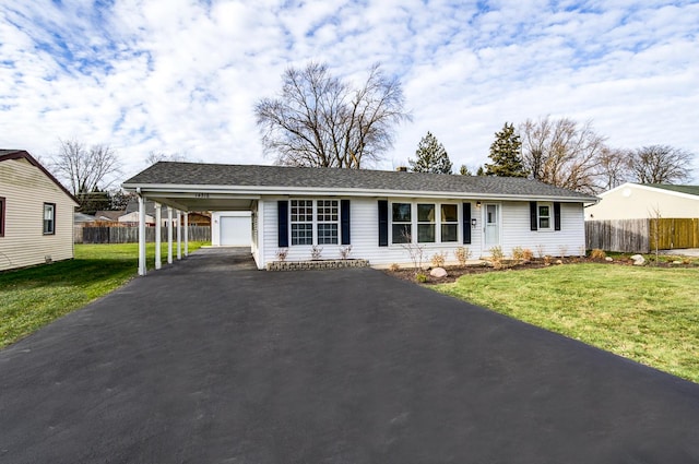 view of front facade featuring driveway, a carport, a front yard, and fence