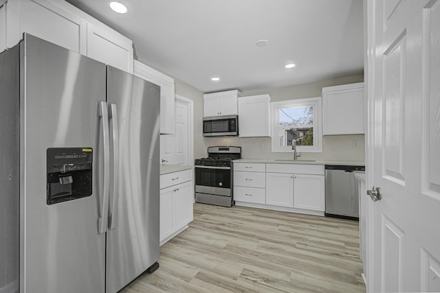 kitchen with white cabinets, appliances with stainless steel finishes, light countertops, and a sink