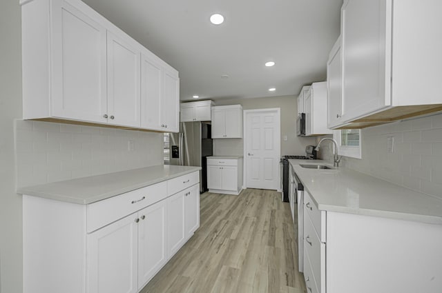 kitchen with light wood-type flooring, appliances with stainless steel finishes, white cabinetry, and light countertops