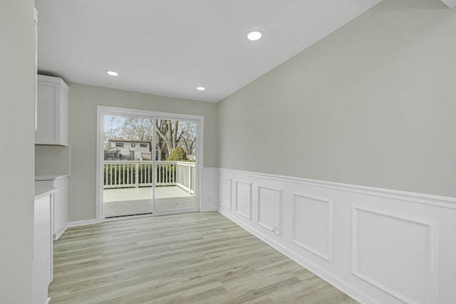 unfurnished dining area featuring recessed lighting, a wainscoted wall, and light wood finished floors