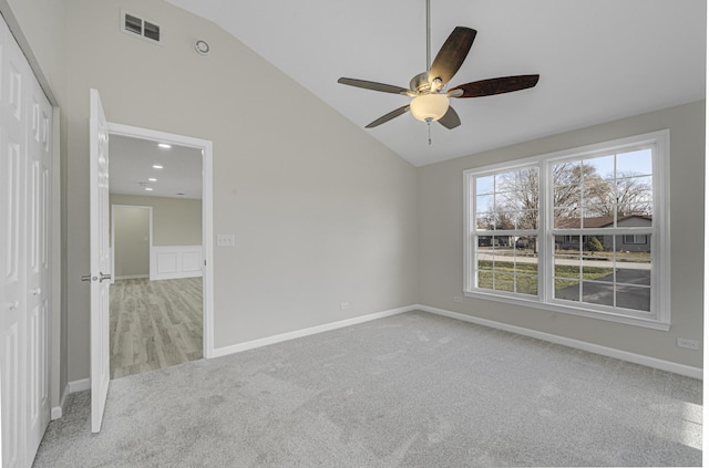 spare room with vaulted ceiling, baseboards, visible vents, and light colored carpet