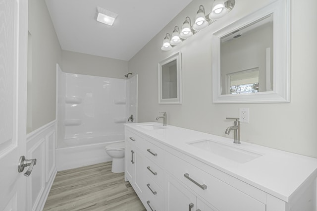 bathroom with double vanity, a sink, toilet, and wood finished floors