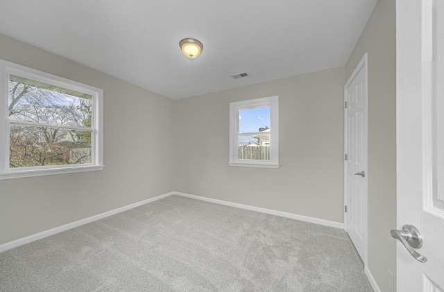 unfurnished room featuring baseboards, visible vents, and light colored carpet