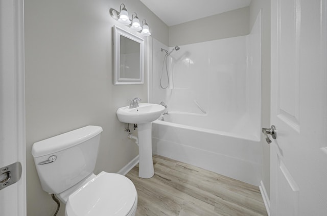 bathroom featuring bathtub / shower combination, wood finished floors, toilet, and baseboards