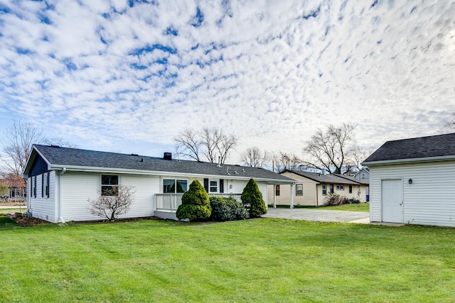 rear view of house featuring driveway, a chimney, and a yard