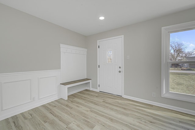 foyer entrance featuring a decorative wall, recessed lighting, baseboards, wainscoting, and light wood finished floors