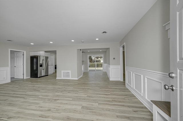 spare room with recessed lighting, visible vents, a decorative wall, and light wood finished floors