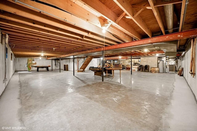 unfinished below grade area featuring water heater and stairs