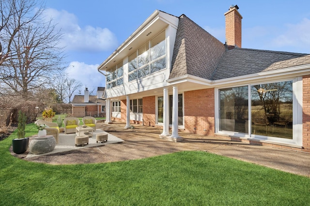 rear view of property featuring a patio, a yard, roof with shingles, brick siding, and a chimney